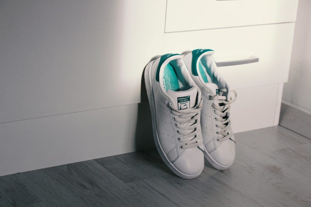 White Adidas Stan Smith Sneakers leaning against the wall