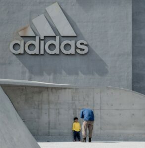 Man Taking Photo of a Child Leaning on Wall with the Adidas logo